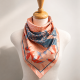 Mannequin wearing a pink floral scarf with a blue border on a plain background