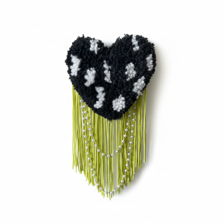 Professional product photo of black and white spotted tufted heart brooch with lime green fringe