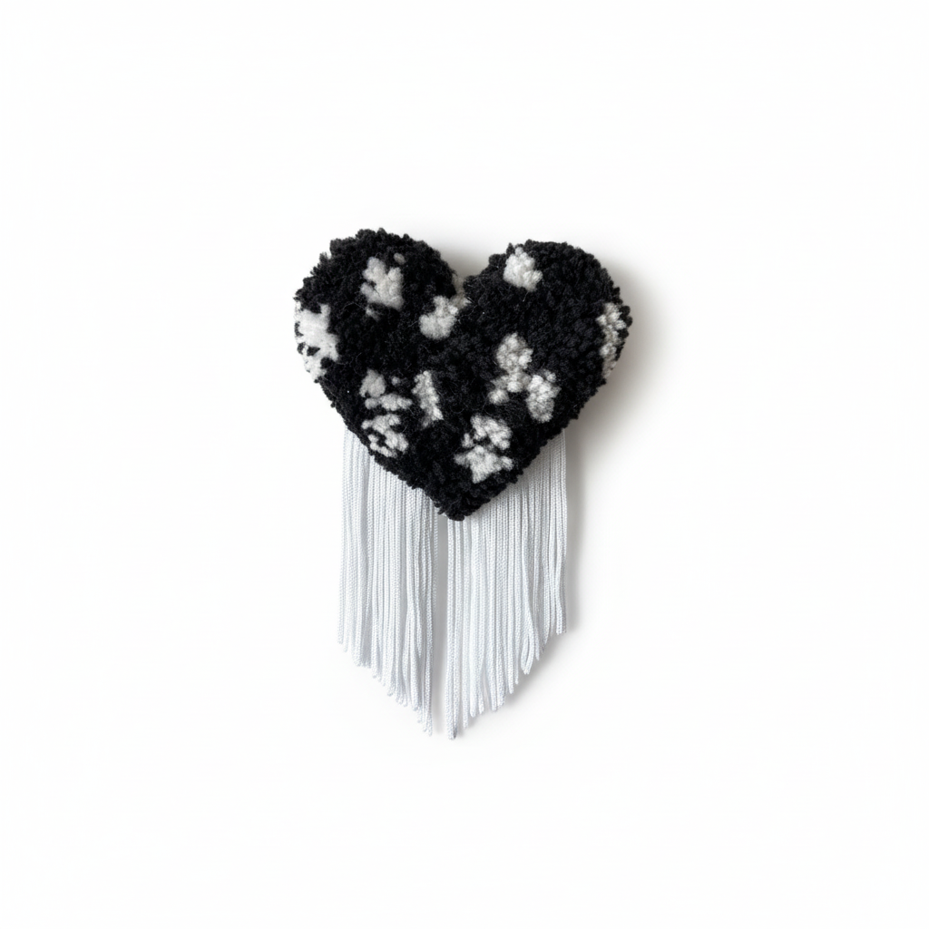 Professional product photo of black and white spotted tufted heart brooch with white fringe