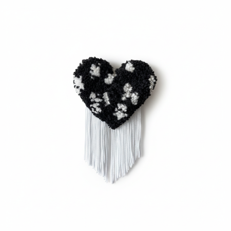 Professional product photo of black and white spotted tufted heart brooch with white fringe