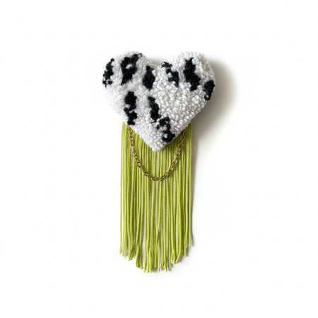 Professional product photo of black and white striped tufted heart brooch with lime green fringe