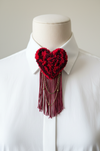 Red and burgundy tufted heart brooch on white button-down shirt collar